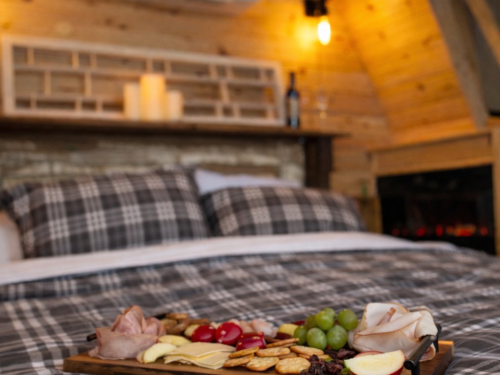 Birchwood Meadow — a charcuterie board and candles on the bed by the fireplace