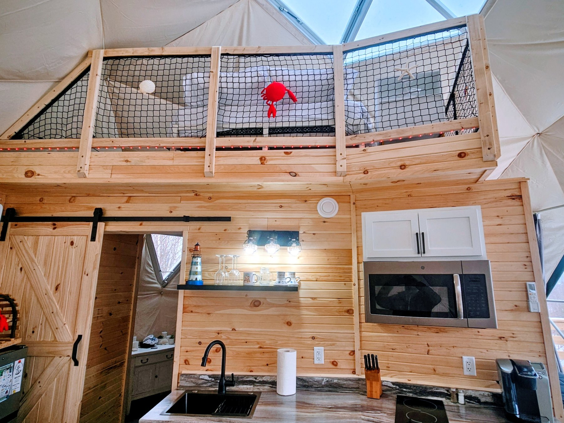Harbor Haven — the loft nook, kitchenette and the barn door to the bathroom